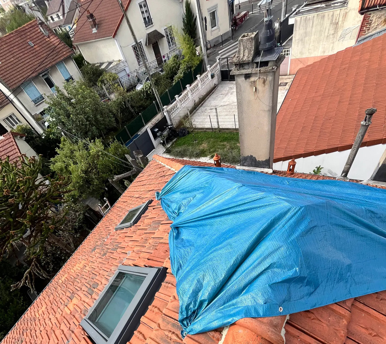 Vue de la toiture bâchée à Villejuif, avec les fenêtres de toit et les pavillons voisins