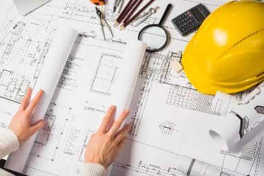 Étude des plans d'un chantier de couverture, casque et outils de l'artisan, dans le Val-de-Marne